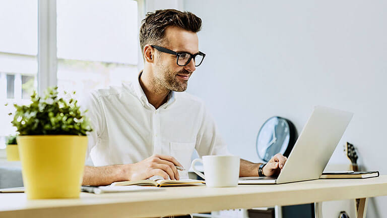 Homme heureux travaillant sur un ordinateur portable depuis son bureau à domicile, ©baranq / Adobe Stock