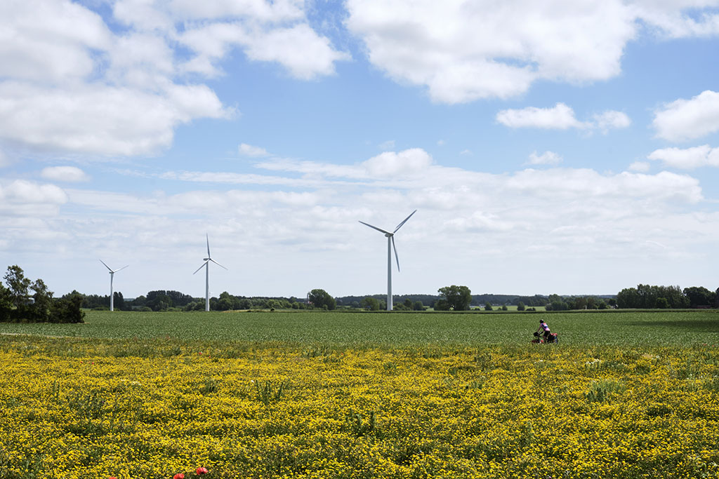 Roman Petibon rides his bike in front of a windmill landscape.