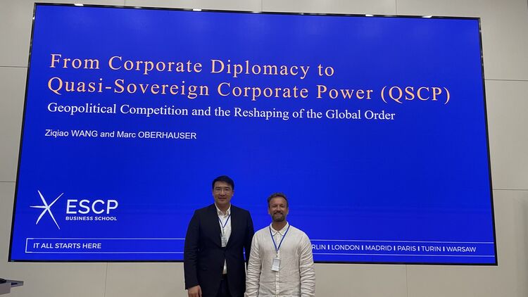 Marc Oberhauser and Ziqiao Wang standing in front of a large screen displaying their presentation on quasi-sovereign corporate power at the World Business Ethics Forum.
