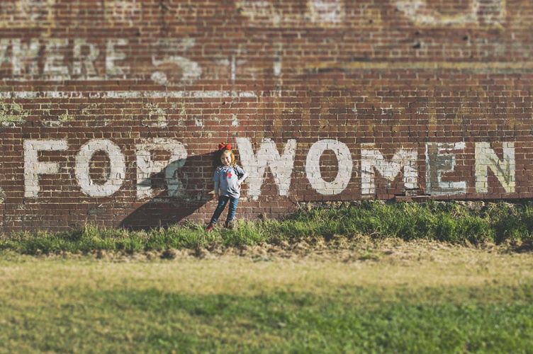 Girl standing near brown building during daytime