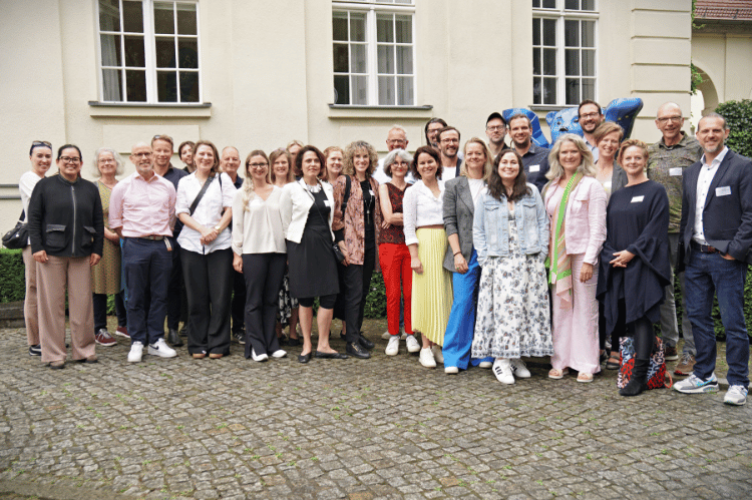 A group of educators, students, and practitioners gather for a photo on the Berlin Campus in front of the Bear