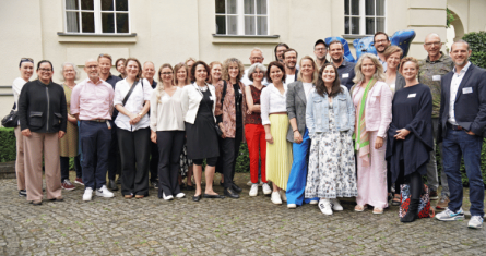 A group of educators, students, and practitioners gather for a photo on the Berlin Campus in front of the Bear