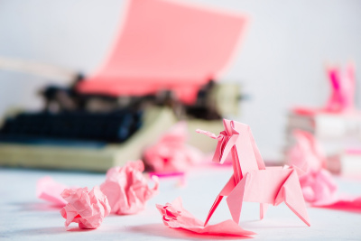 Pink,Origami,Unicorn,With,Crumpled,Paper,Balls,And,A,Typewriter.