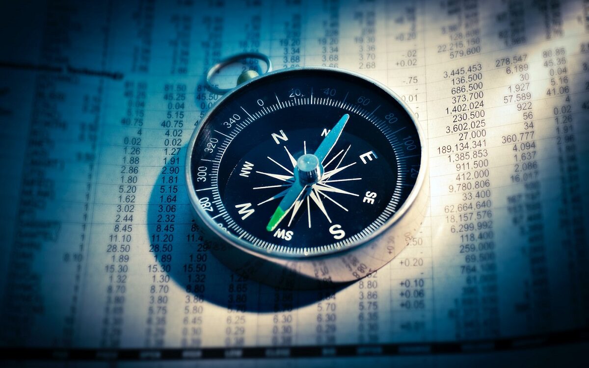 ©AbsolutVision/Unsplash Image of a compass on top of a stock exchange sheet.