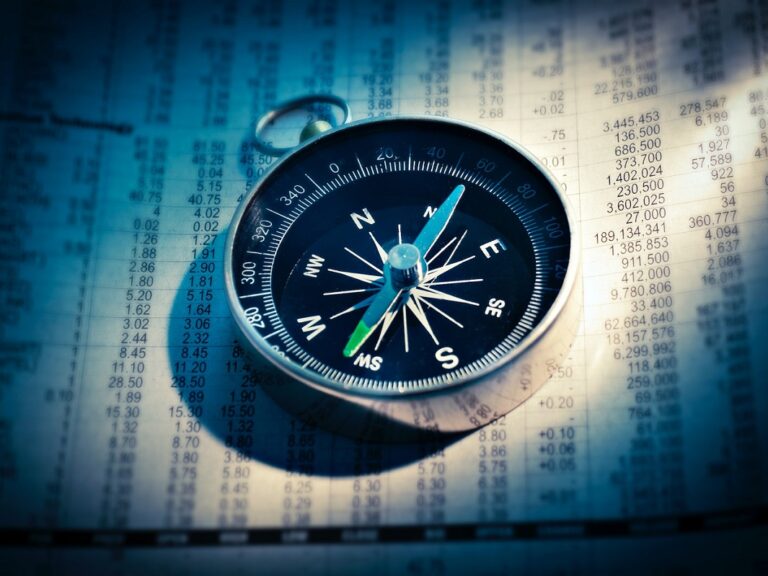 Image of a compass on top of a stock exchange sheet.
