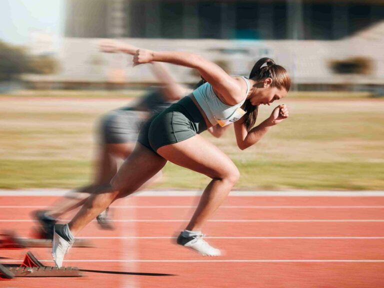A woman running on a track going fast enough that her legs are blurry.