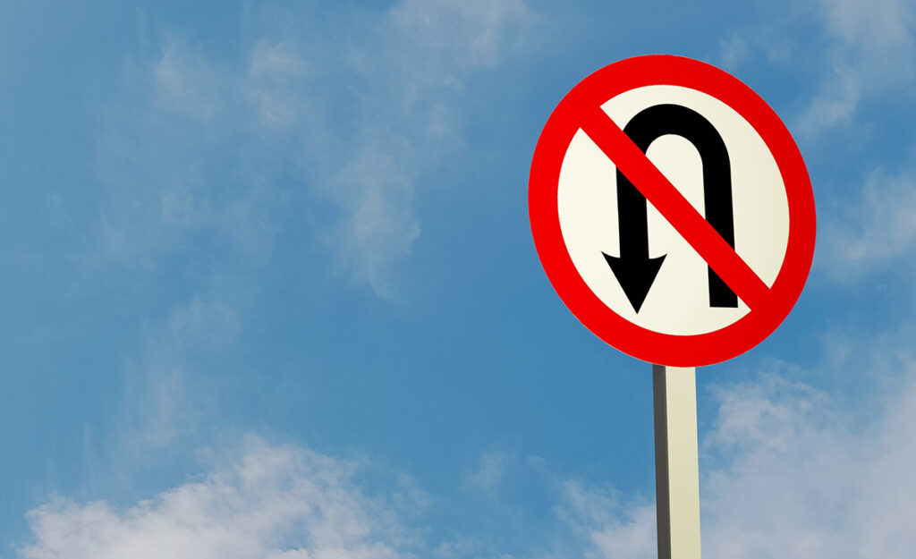 Illustration of a "Do not U-turn" traffic sign and a sky background.