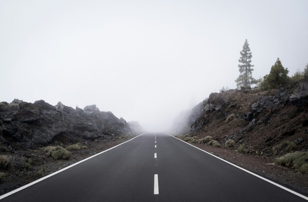 A paved road leads into dense fog.