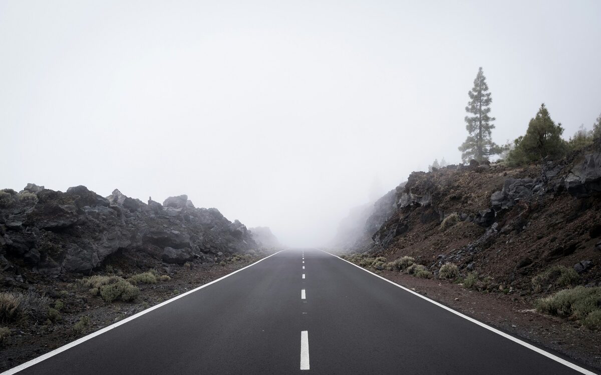 ©Alberto Frias / Unsplash A paved road leads into dense fog.