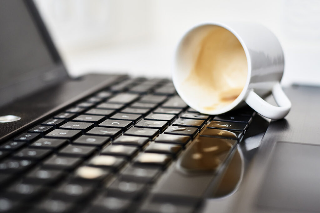 Spill coffee from white cup on the computer laptop keyboard.