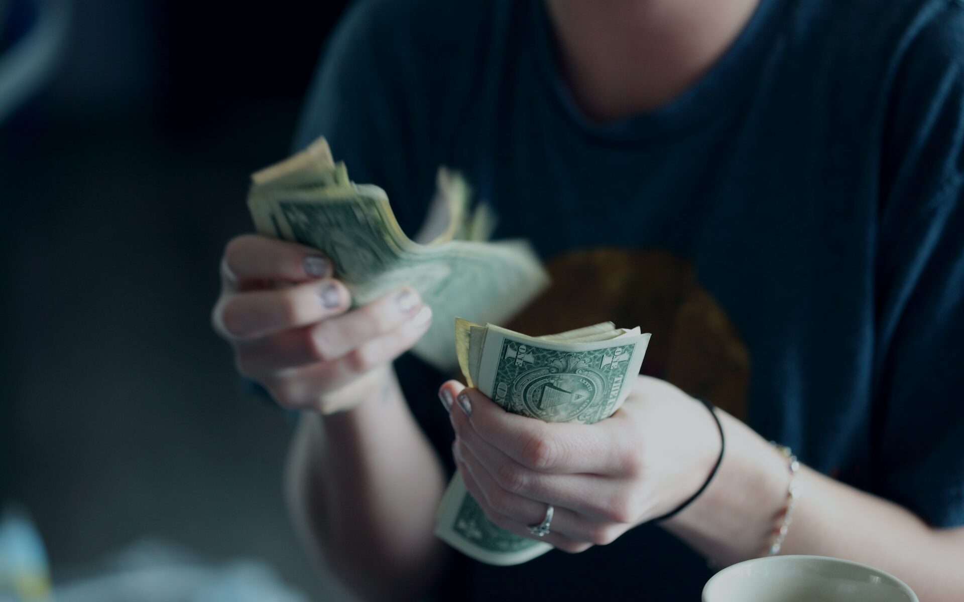 ©Alexander Grey/Unsplash Photo of a woman counting dollar bills.
