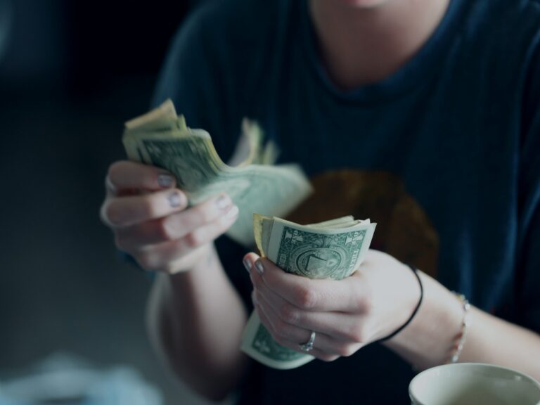 Photo of a woman counting dollar bills.