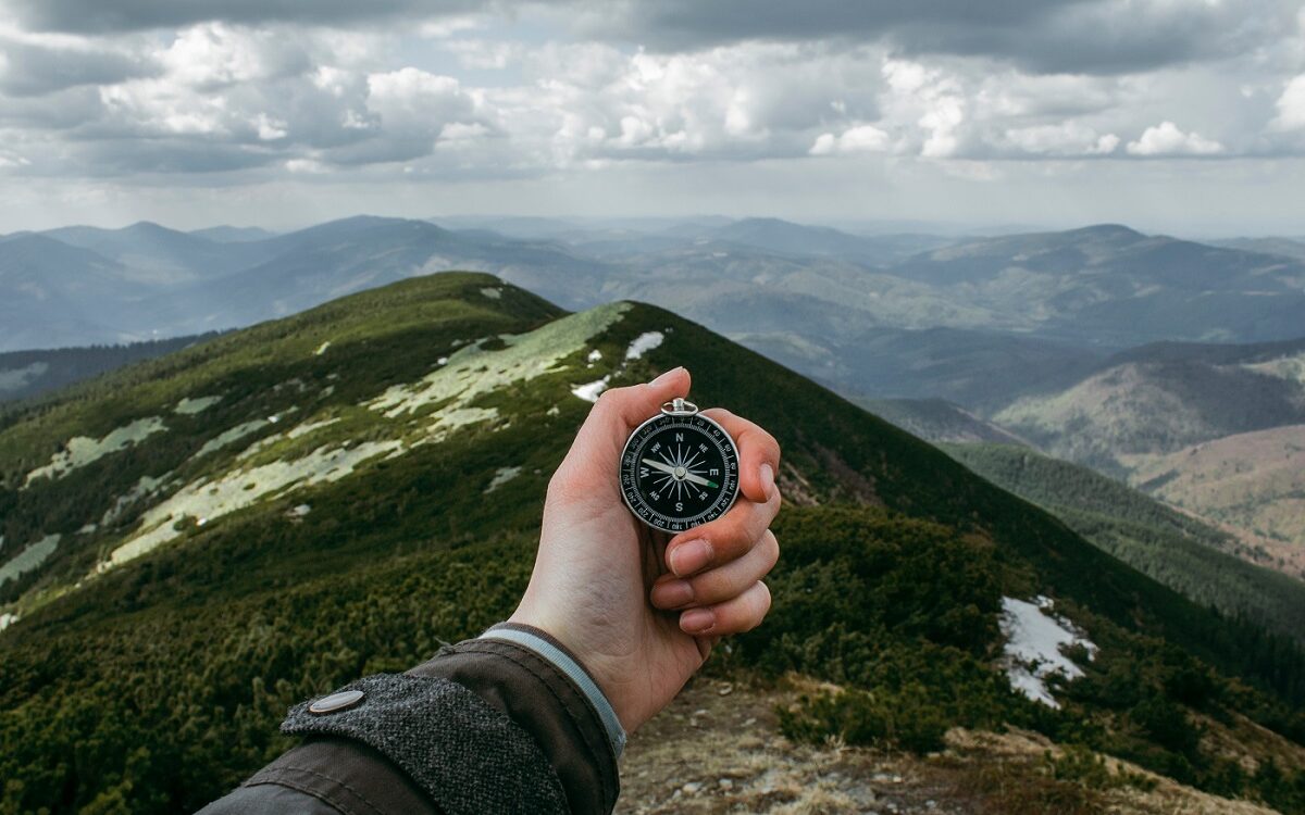 ©Anastasia Petrova/Unsplash Man holding a compass on a mountain