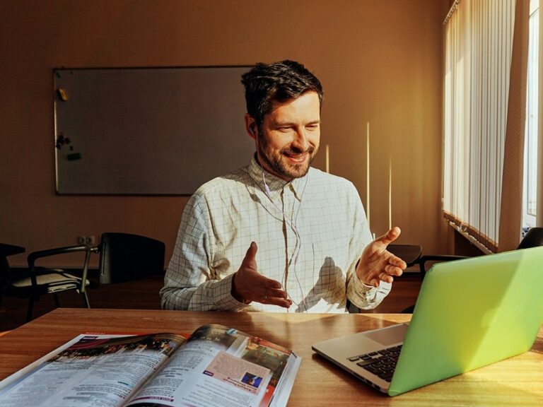 Photo of a man looking at a computer with his hands in the air indicating that he is talking.