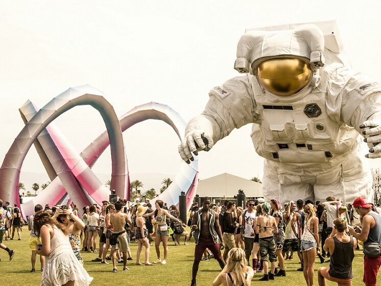 Picture from Coachella. A large blow-up astronaut stands over a crowd dressed in festival clothing.