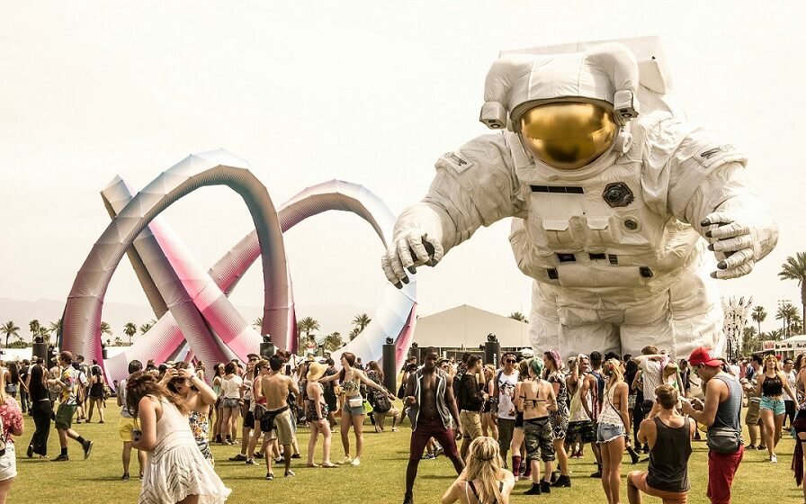 ©Andrew Ruiz / Unsplash Picture from Coachella. A large blow-up astronaut stands over a crowd dressed in festival clothing.