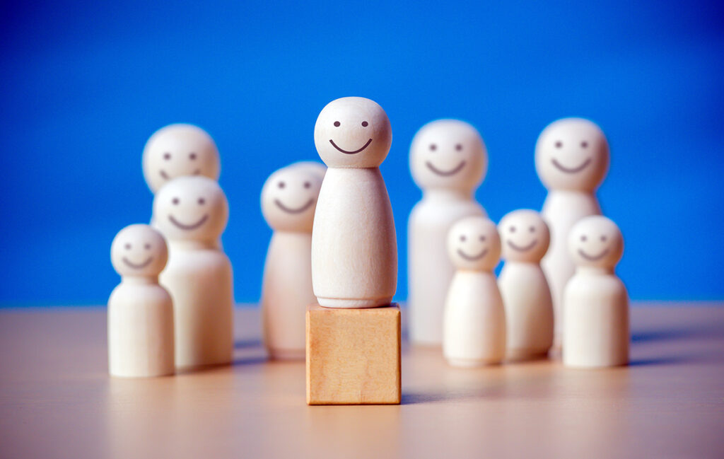 Wooden figure standing on the wooden block to talking leadingship for influence, empowerment and inspiration for crowd.