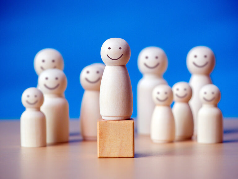 Wooden figure standing on the wooden block to talking leadingship for influence, empowerment and inspiration for crowd.