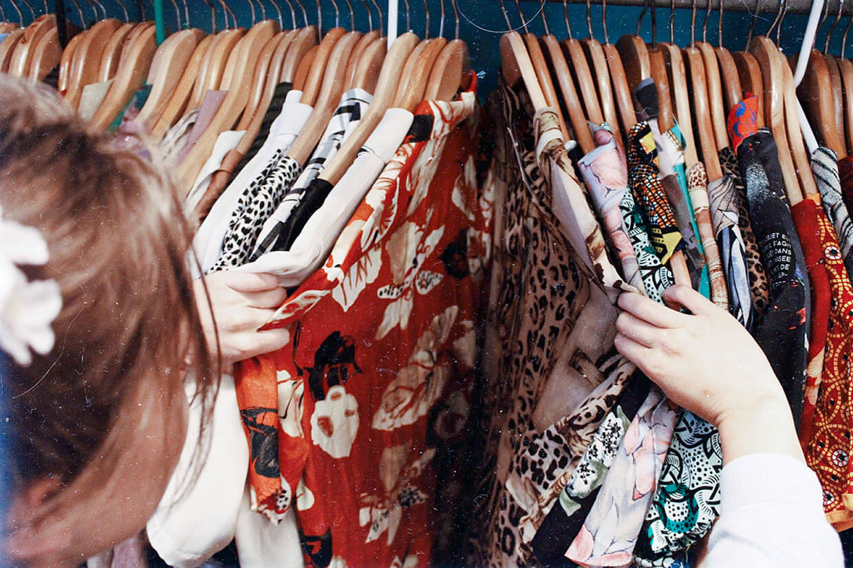Person holding assorted clothes in wooden hanger, © Becca McHaffie / Unsplash
