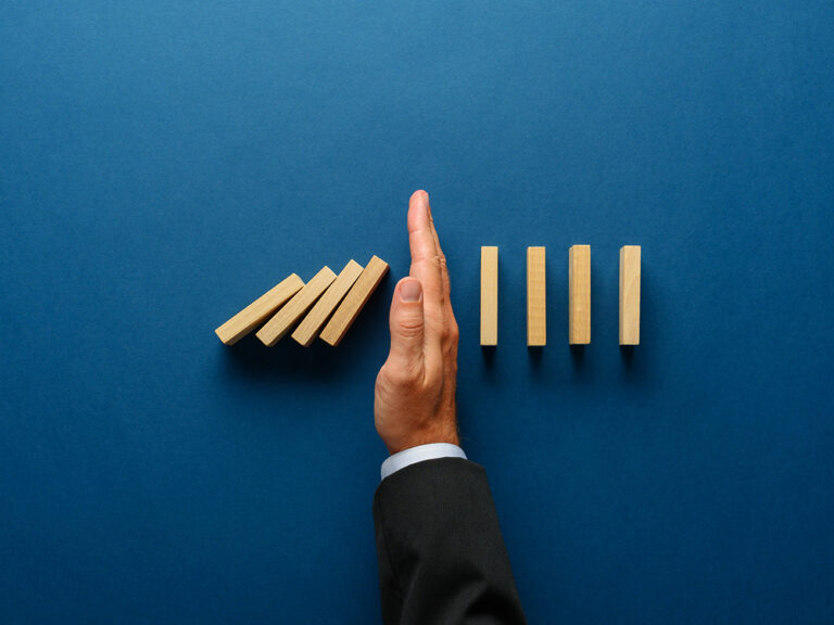 Photo of a hand blocking falling dominos
