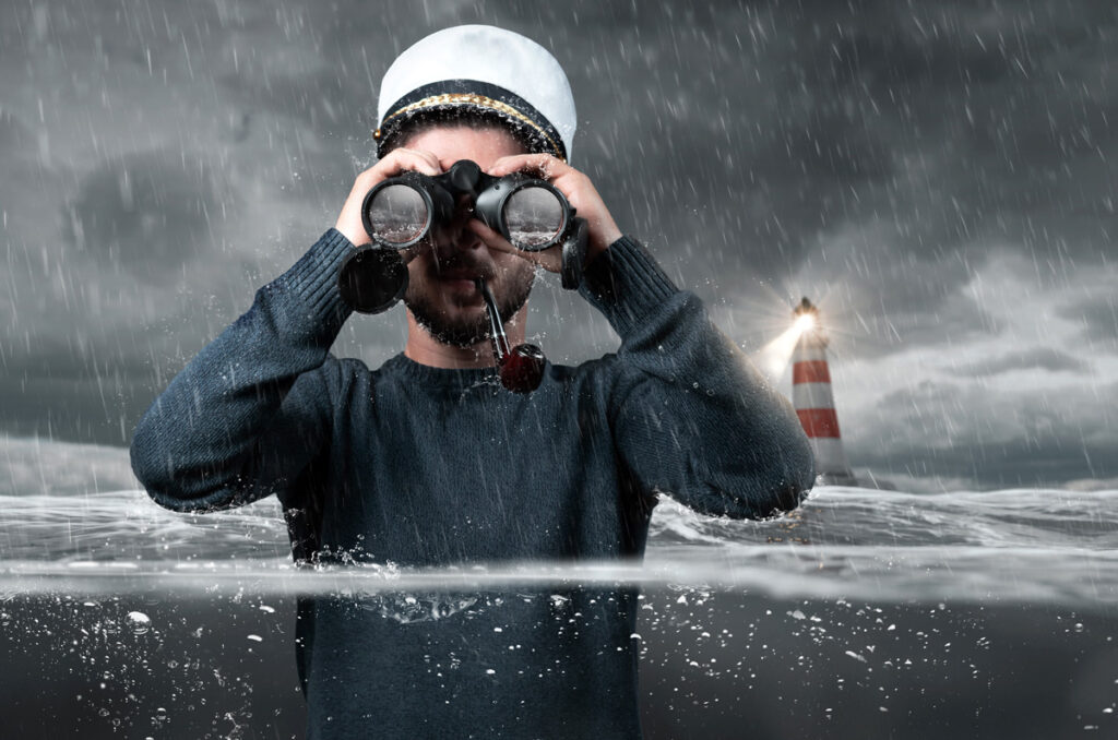 Shipwrecked captain standing underwater and watching with binoculars