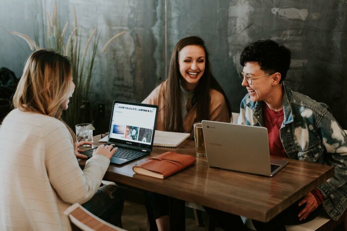 Picture of three young women sitting around a table, talking and laughing.