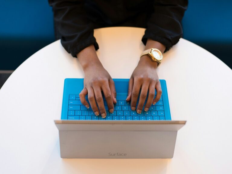 Picture of women's hands from above typing on a computer keyboard.