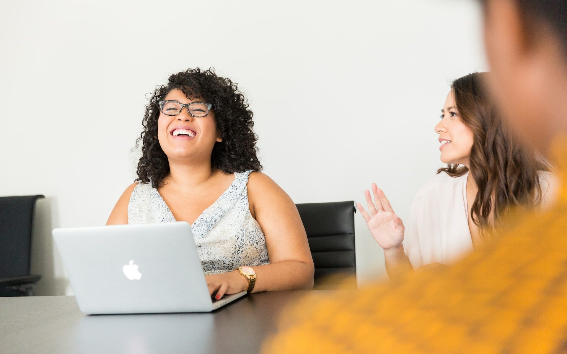 ©Christina/Unsplash Photo of a woman laughing with her colleagues during a meeting