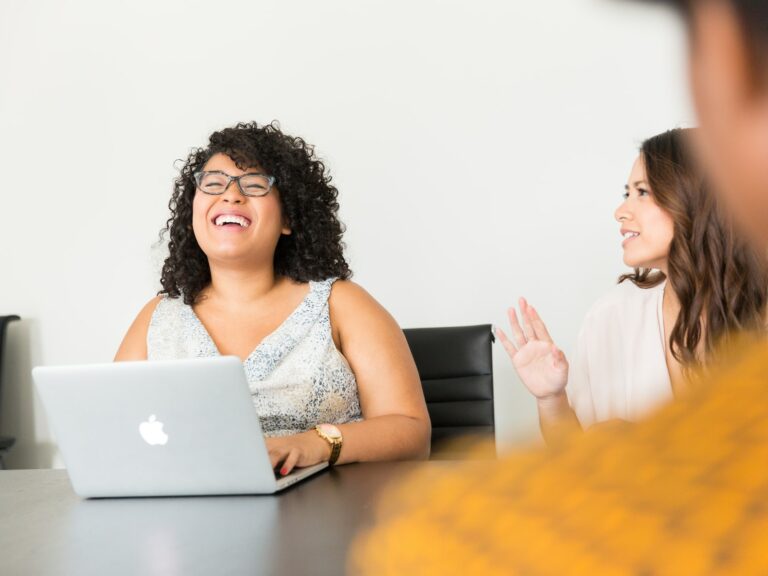 ©Christina/Unsplash Photo of a woman laughing with her colleagues during a meeting
