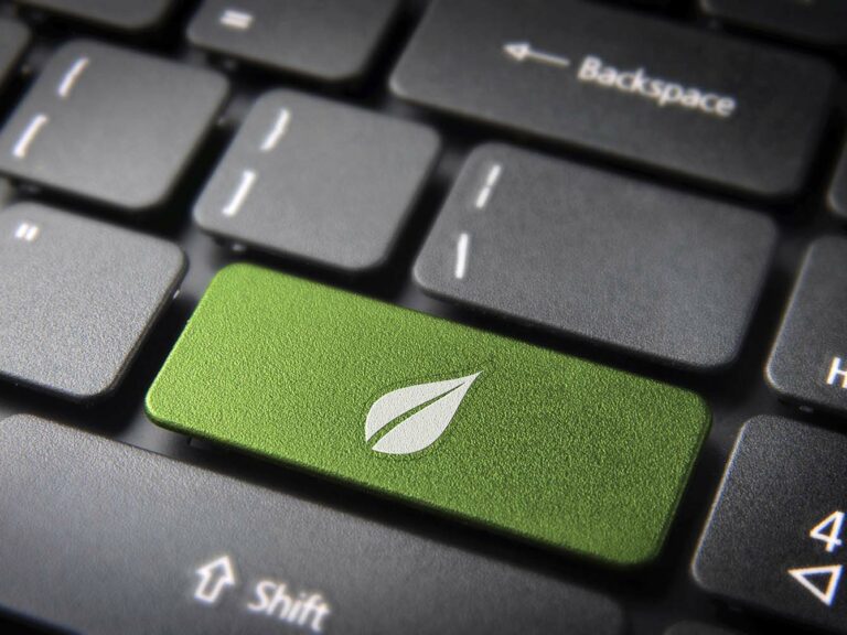 Green energy key with leaf icon on laptop keyboard.