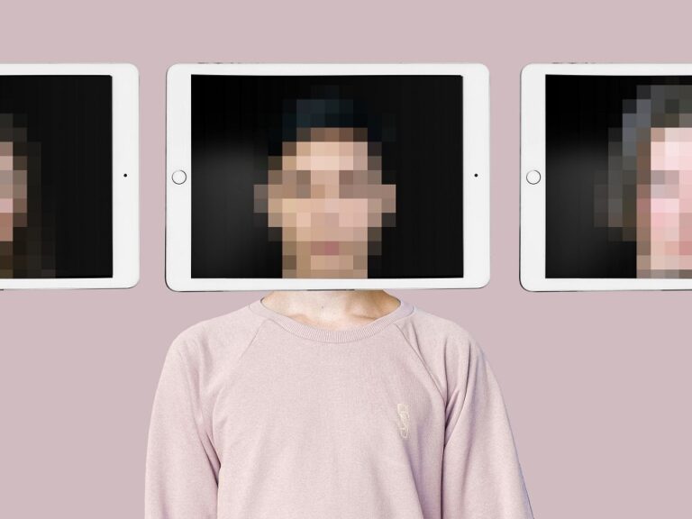 A person stands in front of a pink wall. An iPad is being held in front of their face and the image of their face is distorted, so you can't be sure who you're seeing.