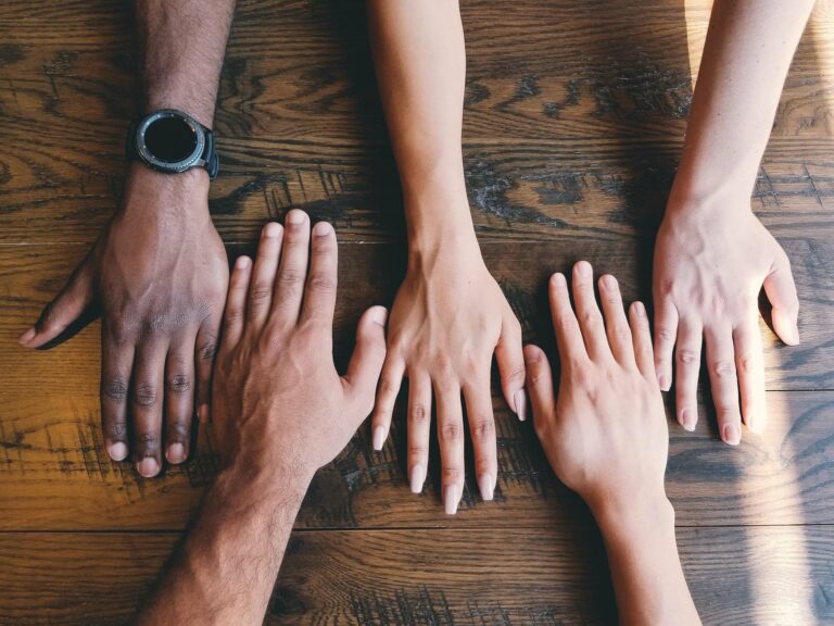 Diversity cannot succeed without inclusion. Hands side by side on a table.