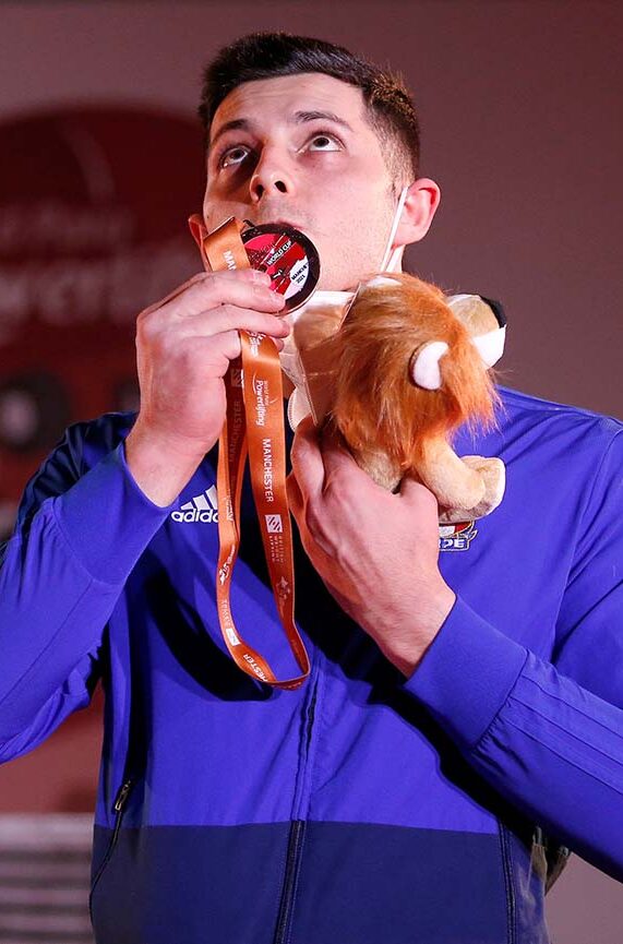 Photo of powerlifting athlete Donato Telesca kissing his medal in celebration