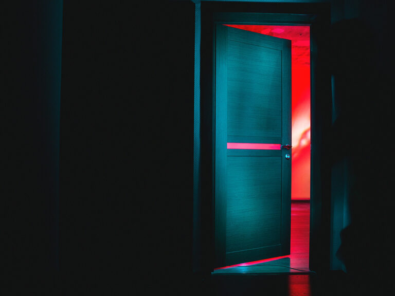 Door opening from a black room into a brightly colored room