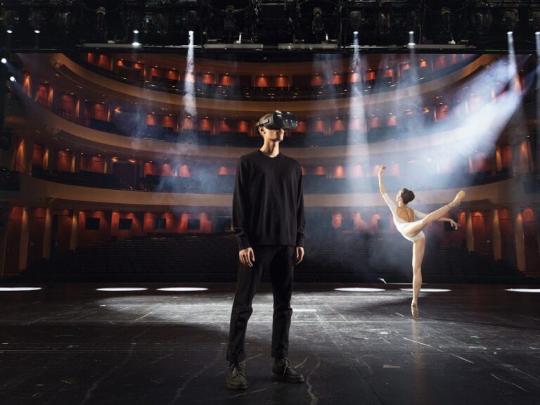 Image of a man using a VR headset on a stage with a ballerina in the background.