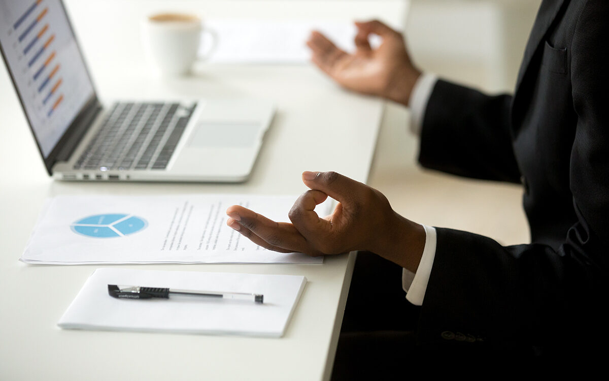 fizkes-AdobeStock Businessman in suit practicing meditation at workplace to reduce work stress or develop concentration.