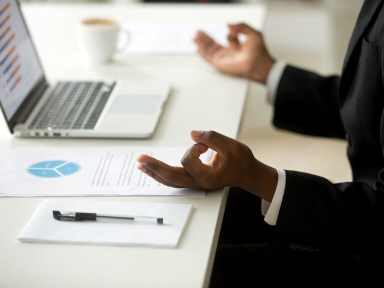 fizkes-AdobeStock Businessman in suit practicing meditation at workplace to reduce work stress or develop concentration.