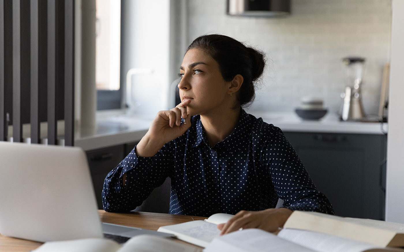 Fizkes/AdobeStock Photo of a young woman, Generation Z, thinking while she works.