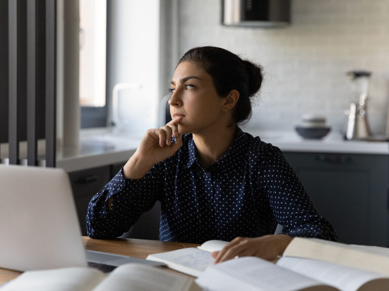Photo of a young woman, Generation Z, thinking while she works.