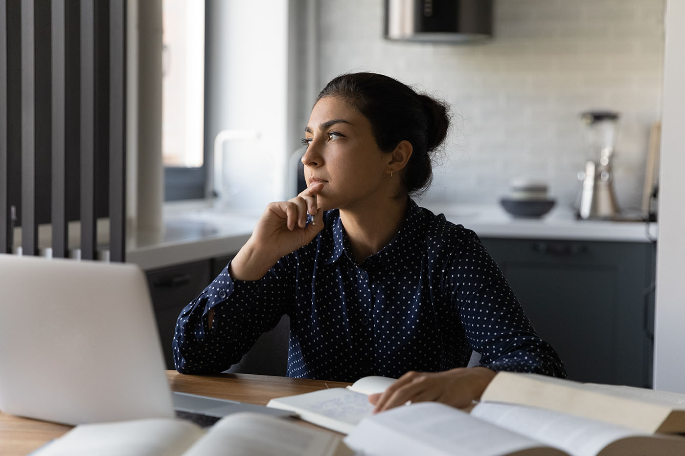 Photo of a young woman, Generation Z, thinking while she works.