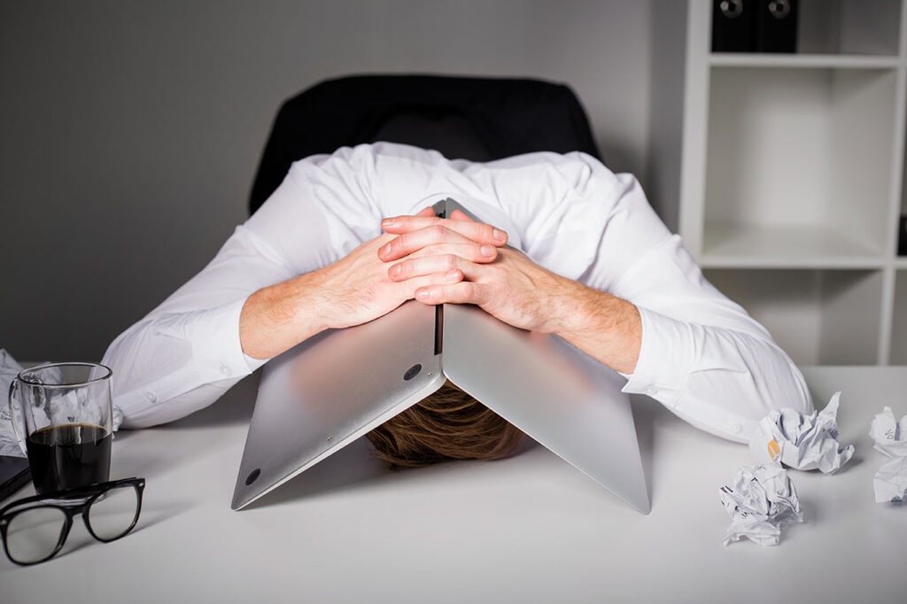 Man hiding under laptop, © Getty / Grinvalds