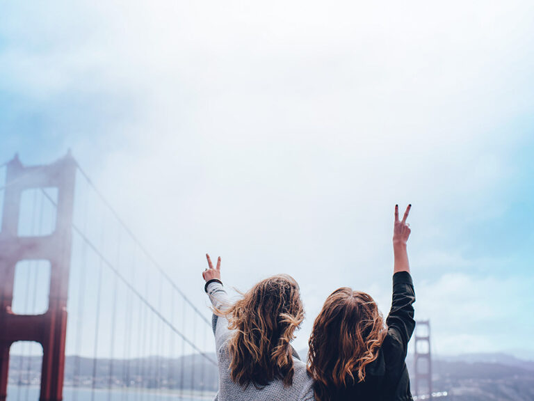 Two women making peace sign near the Golden Gate bridge, © Ian Schneider / Unsplash