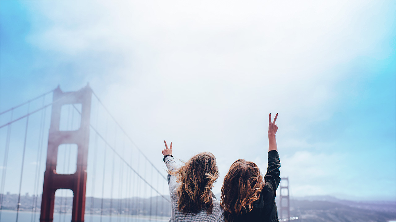 Two women making peace sign near the Golden Gate bridge, © Ian Schneider / Unsplash