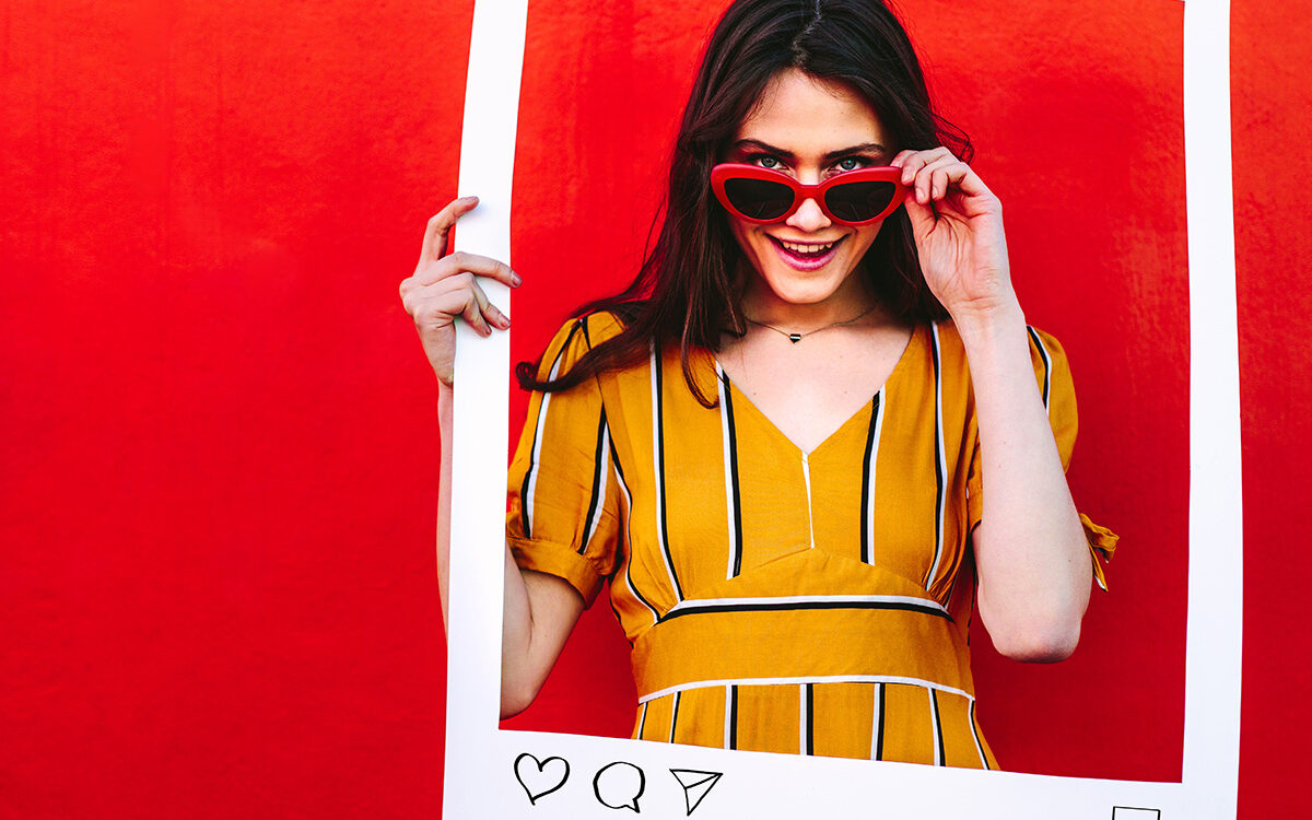 © Jacob Lund – AdobeStock Woman posing with social network post photo frame