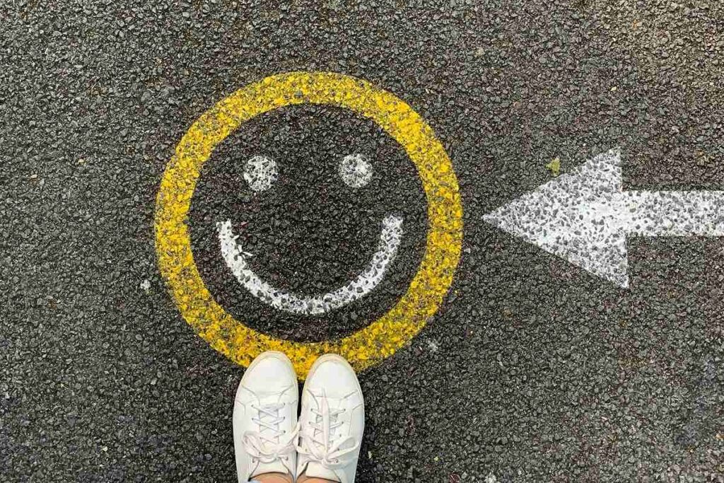 A smiley face painted on a street with a painted arrow pointing to it