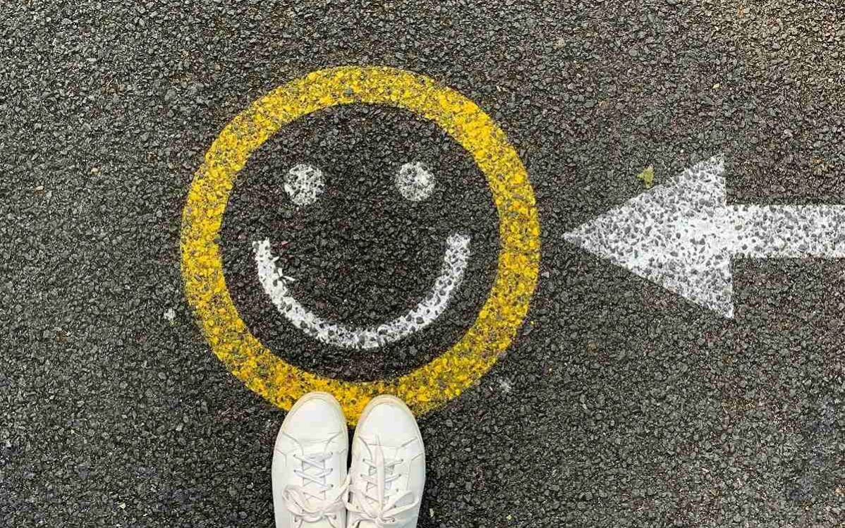 A smiley face painted on a street with a painted arrow pointing to it