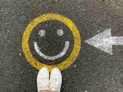 A smiley face painted on a street with a painted arrow pointing to it