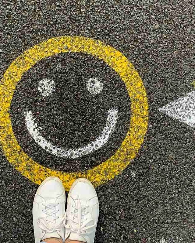 A smiley face painted on a street with a painted arrow pointing to it