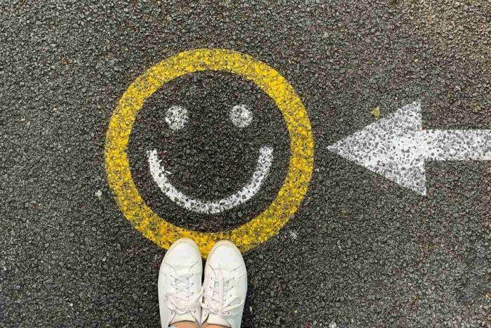 A smiley face painted on a street with a painted arrow pointing to it