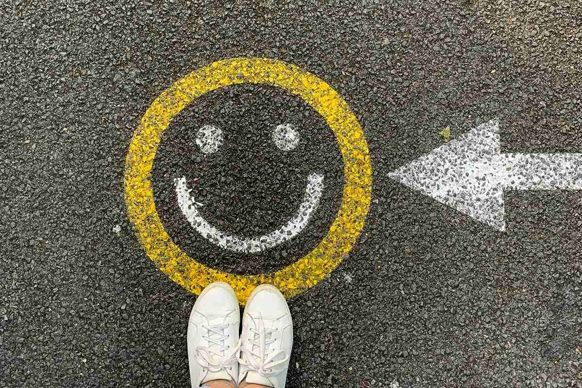 A smiley face painted on a street with a painted arrow pointing to it